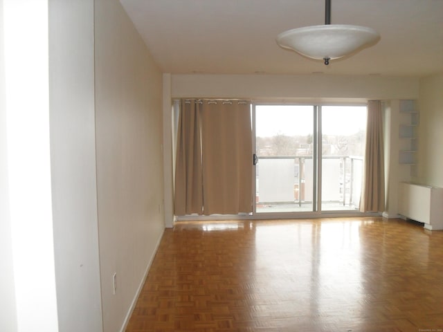 unfurnished room with radiator heating unit and baseboards