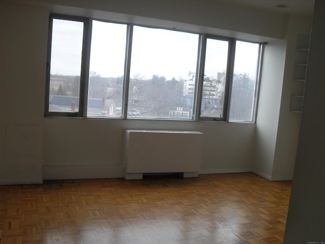 unfurnished room with radiator heating unit and a wealth of natural light