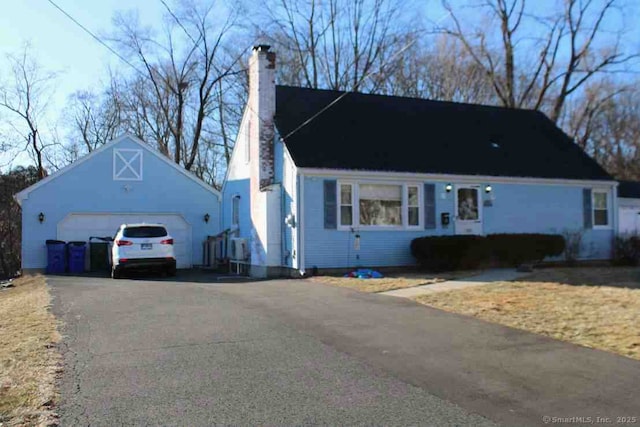 view of front of home featuring a garage, a chimney, and an outdoor structure