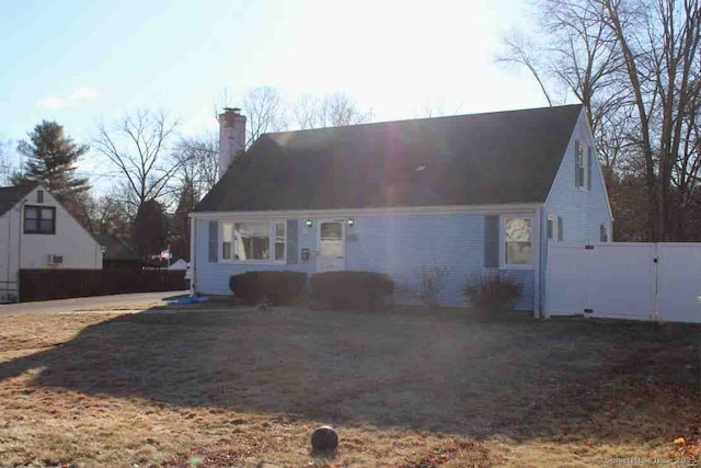 cape cod house featuring a gate, fence, and a chimney