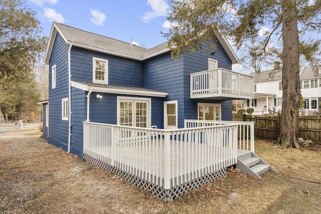 back of property with a deck, fence, and a balcony