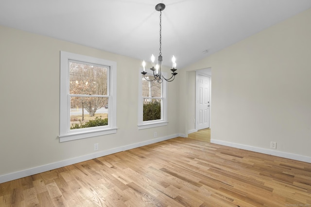 unfurnished dining area featuring light wood-style floors, baseboards, vaulted ceiling, and an inviting chandelier