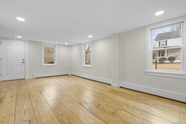 empty room featuring wood-type flooring, a baseboard heating unit, and recessed lighting