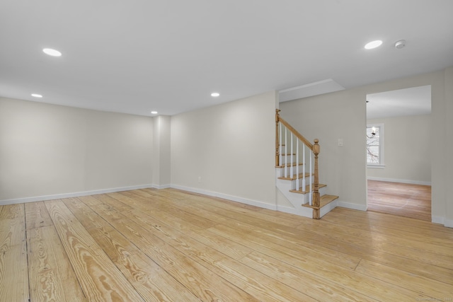 unfurnished room featuring recessed lighting, wood-type flooring, stairway, and baseboards