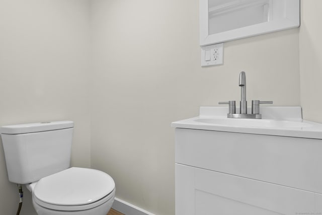 bathroom with toilet, baseboards, and vanity