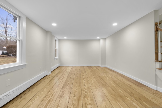 unfurnished room featuring light wood finished floors, baseboard heating, and baseboards