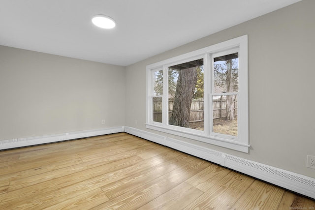 spare room featuring baseboard heating, light wood-style flooring, and baseboards