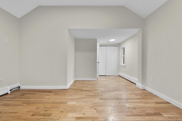 empty room featuring vaulted ceiling, light wood-style flooring, and baseboards