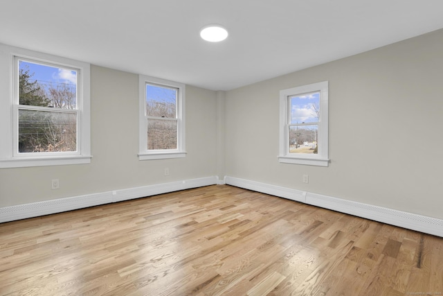 empty room with baseboards, baseboard heating, and wood finished floors