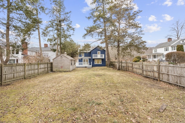 view of yard with a residential view, a fenced backyard, an outdoor structure, and a shed