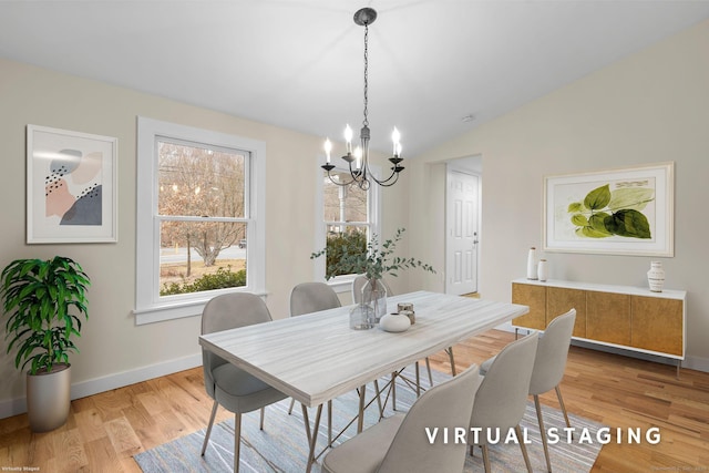 dining space featuring light wood-type flooring, baseboards, vaulted ceiling, and a chandelier