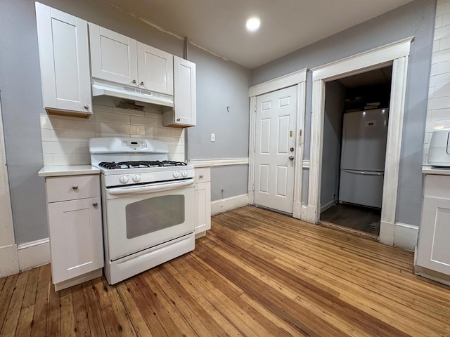 kitchen with under cabinet range hood, light countertops, light wood-style flooring, white appliances, and white cabinetry