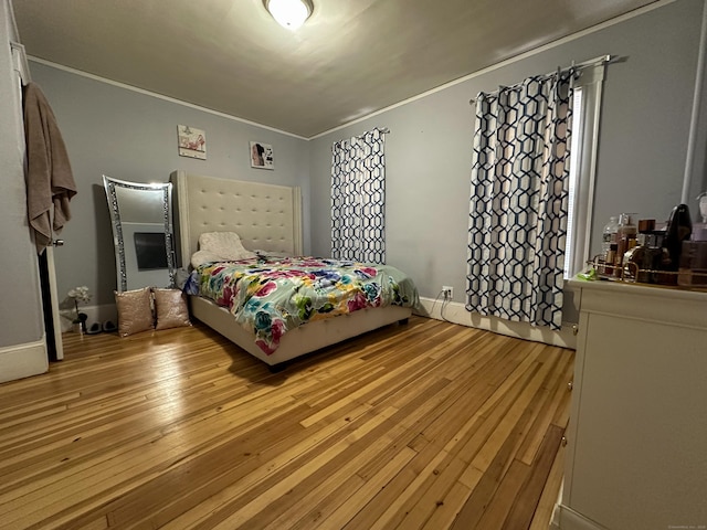 bedroom featuring light wood-style flooring, baseboards, and ornamental molding