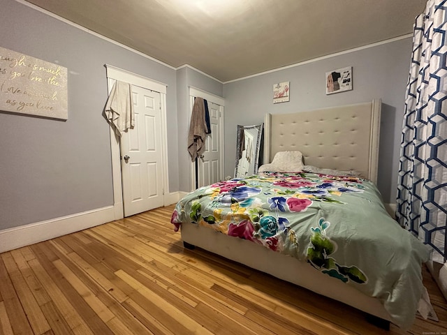 bedroom with hardwood / wood-style flooring, baseboards, and ornamental molding