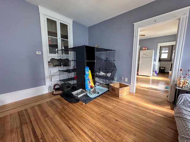 bedroom with freestanding refrigerator, baseboards, and hardwood / wood-style flooring