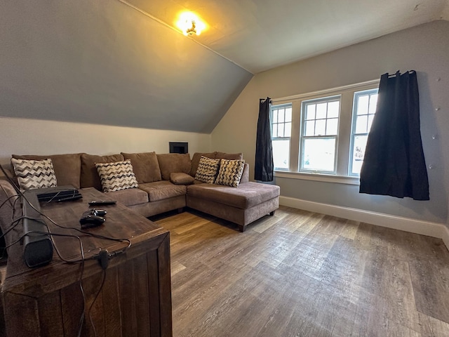 living area featuring lofted ceiling, wood finished floors, and baseboards