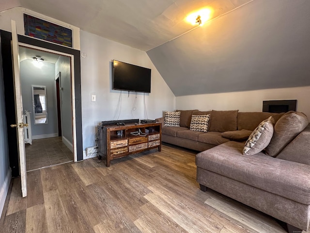 living area featuring baseboards, lofted ceiling, and wood finished floors