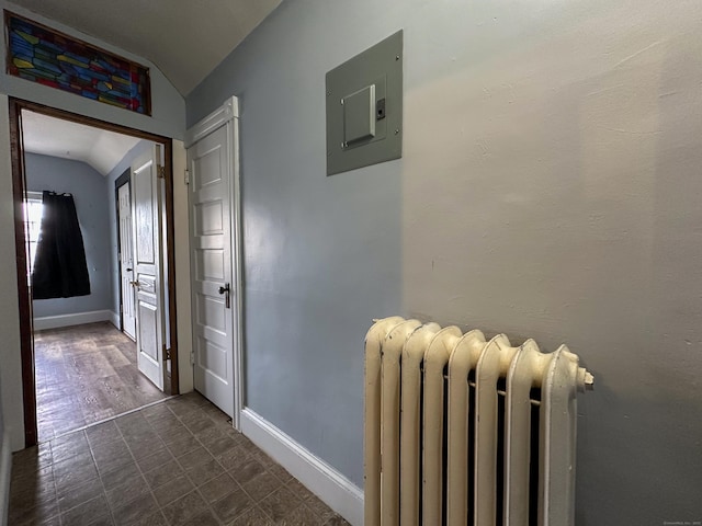 hallway featuring electric panel, radiator, baseboards, and lofted ceiling