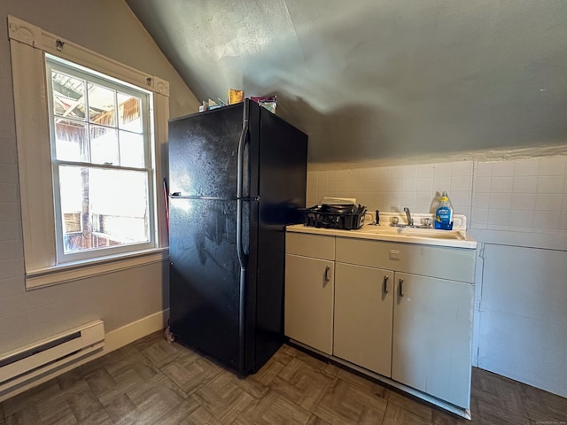 kitchen featuring a baseboard heating unit, light countertops, vaulted ceiling, freestanding refrigerator, and a textured ceiling