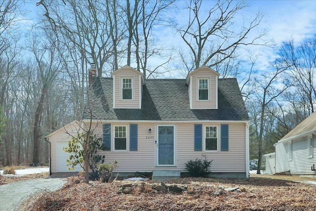 new england style home with driveway, a garage, entry steps, a chimney, and roof with shingles