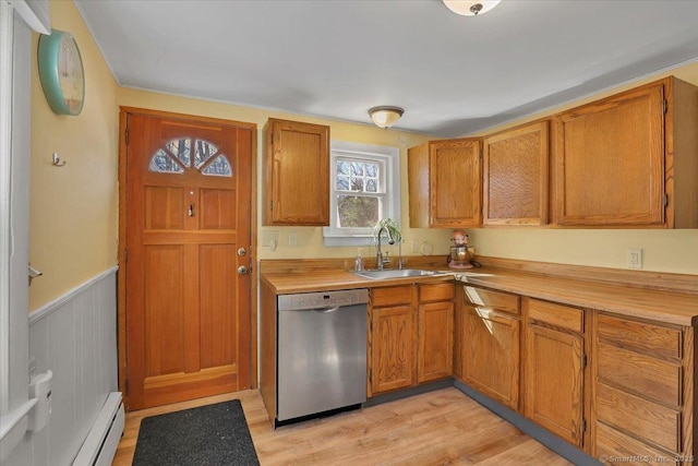 kitchen with a sink, light countertops, stainless steel dishwasher, and wainscoting