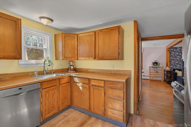 kitchen featuring light wood-style flooring, stainless steel appliances, a sink, light countertops, and brown cabinetry