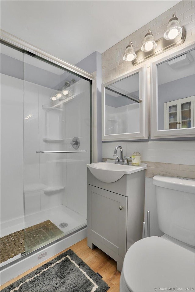 full bath with vanity, a shower stall, toilet, and wood finished floors