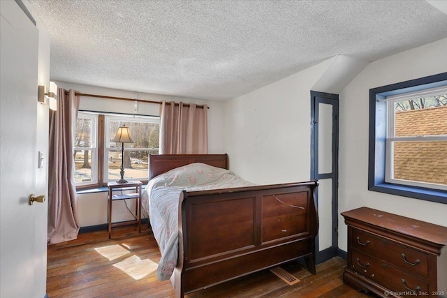 bedroom featuring wood-type flooring, multiple windows, a textured ceiling, and baseboards