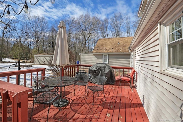 deck with outdoor dining space, area for grilling, and an outdoor structure