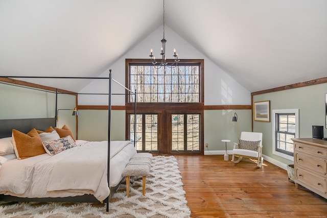 bedroom featuring a notable chandelier, high vaulted ceiling, baseboards, and wood finished floors