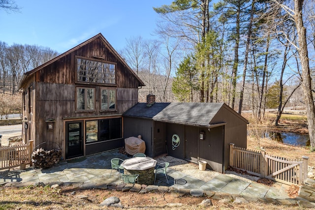 back of house featuring a patio, fence, and a chimney