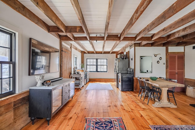 kitchen with electric range, beamed ceiling, light wood finished floors, wooden walls, and light countertops