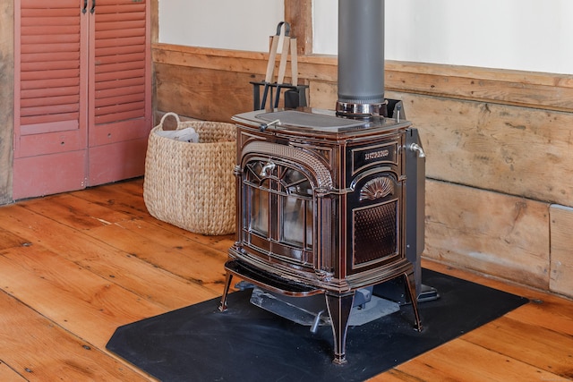 details featuring a wainscoted wall, wood finished floors, wood walls, and a wood stove