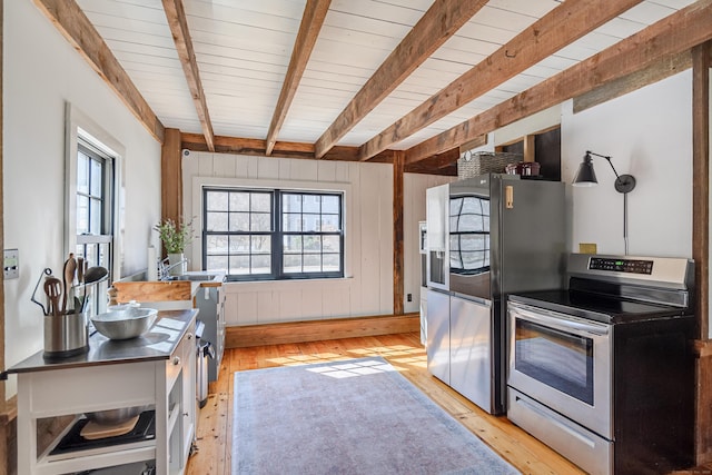 kitchen featuring beamed ceiling, a healthy amount of sunlight, stainless steel appliances, and stainless steel countertops