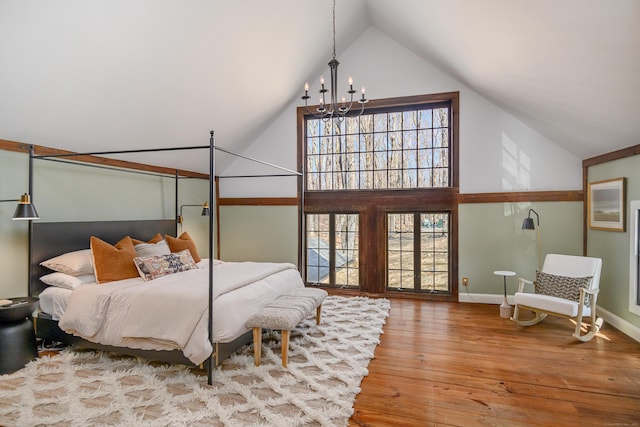 bedroom with an inviting chandelier, high vaulted ceiling, baseboards, and wood-type flooring