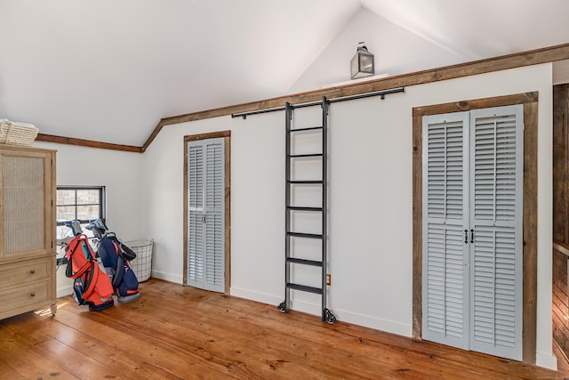 interior space featuring baseboards, lofted ceiling, light wood-style flooring, and a barn door