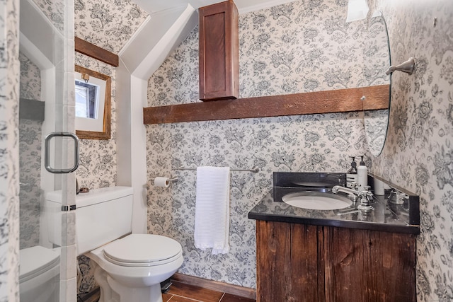 bathroom with toilet, vanity, and wallpapered walls