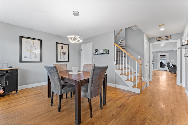 dining room featuring baseboards, stairs, and light wood finished floors