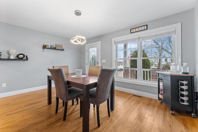 dining room with visible vents, light wood-style flooring, an inviting chandelier, and baseboards