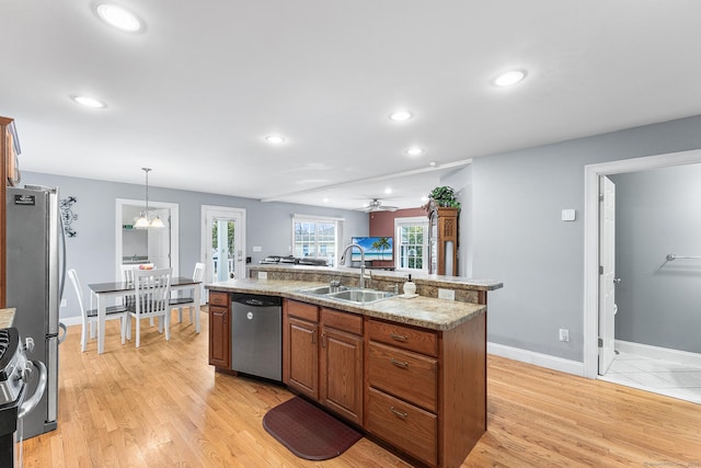 kitchen featuring a center island with sink, recessed lighting, a sink, stainless steel appliances, and light wood-type flooring