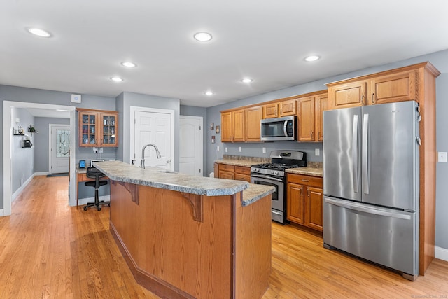 kitchen featuring light wood-type flooring, a kitchen island with sink, a kitchen breakfast bar, recessed lighting, and stainless steel appliances