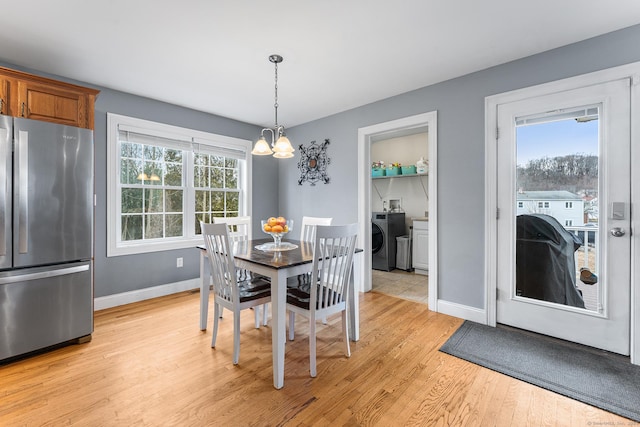 dining space with a notable chandelier, washer / clothes dryer, baseboards, and light wood-type flooring