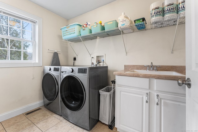 laundry area with visible vents, baseboards, washing machine and dryer, light tile patterned floors, and a sink