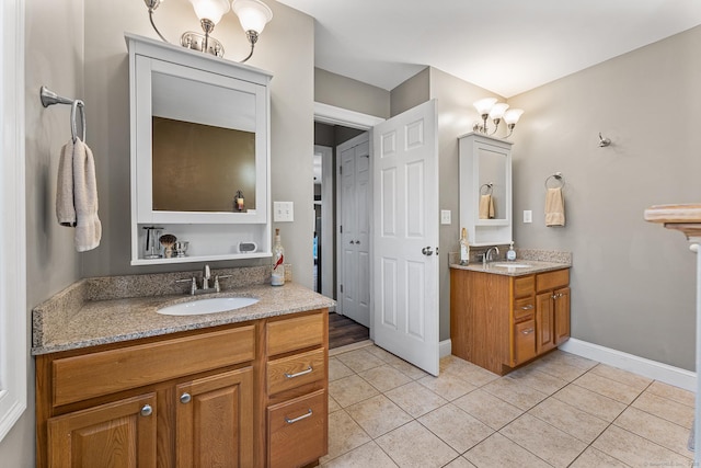 full bath with a sink, baseboards, two vanities, and tile patterned floors