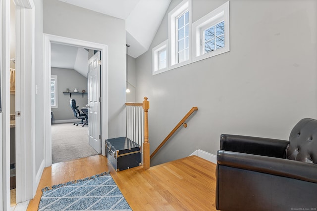 stairs with lofted ceiling, wood finished floors, and baseboards