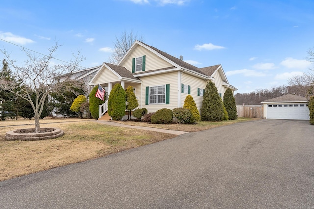 view of front of house featuring a garage, a front yard, an outdoor structure, and fence