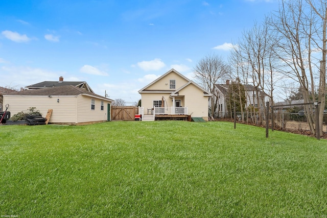 rear view of house with a yard, a deck, a fenced backyard, and a gate