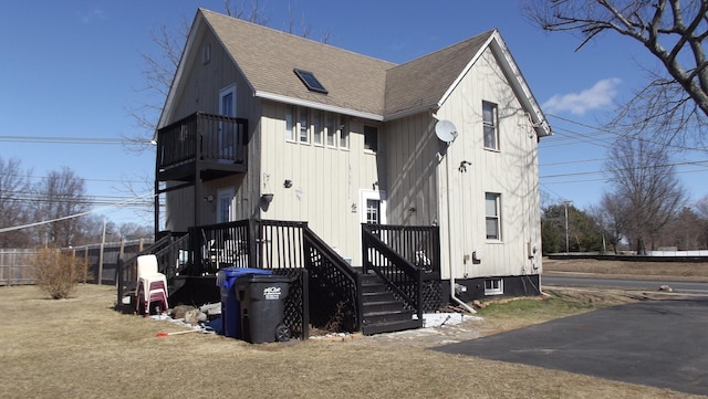 view of front facade featuring a shingled roof and a balcony