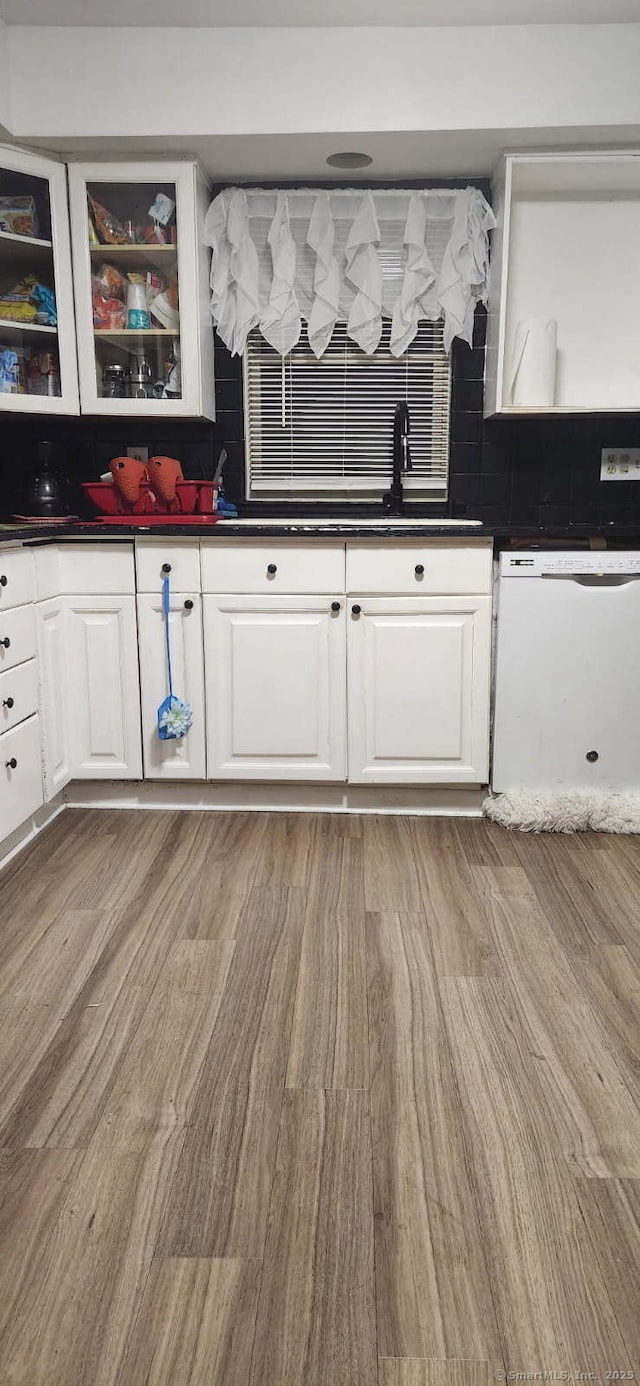 kitchen featuring dark countertops, white cabinetry, and white dishwasher