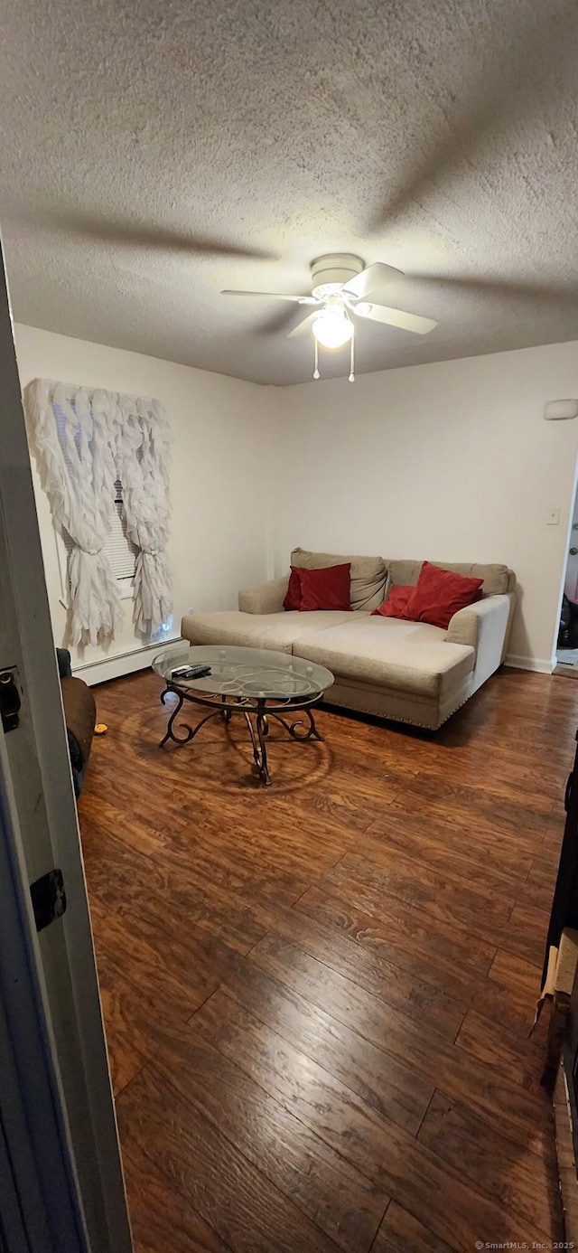 living area featuring ceiling fan, a textured ceiling, baseboard heating, and wood finished floors